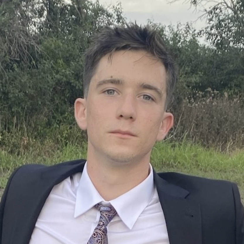 A young person in a suit looks at the camera.