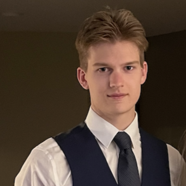 A young person in a vest and tie looks at the camera.