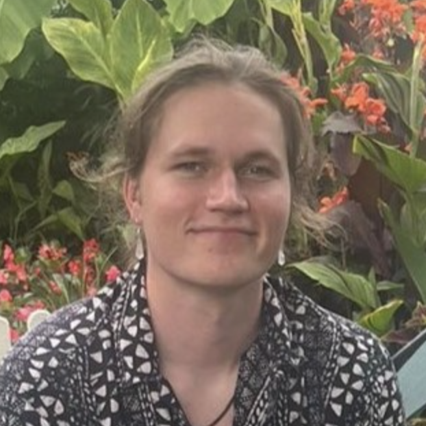 A young person with a patterned shirt smiles. 